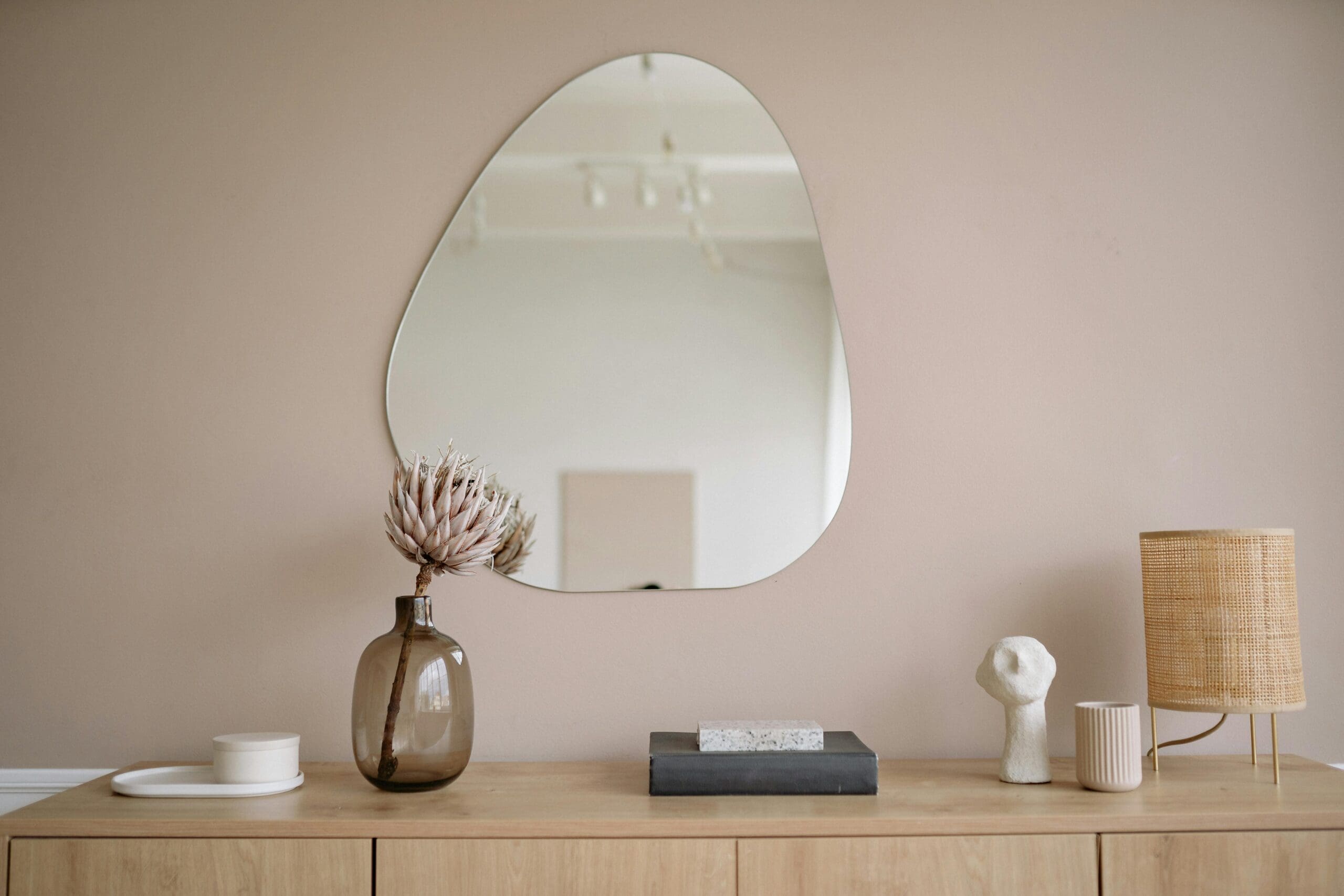 Decorative interior scene in a Centennial, CO hormone therapy clinic featuring a modern dresser with dried flowers, a sculptural lamp, and a minimalist mirror.