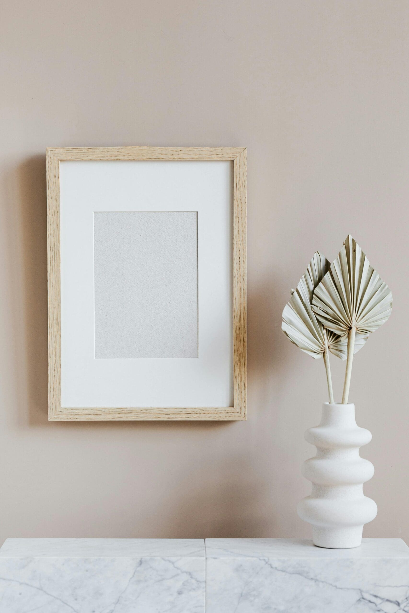 Minimal beige home decor with a white vase, palm fronds, and a wood frame, used as featured image for a perimenopause vs menopause blog post about hormone health