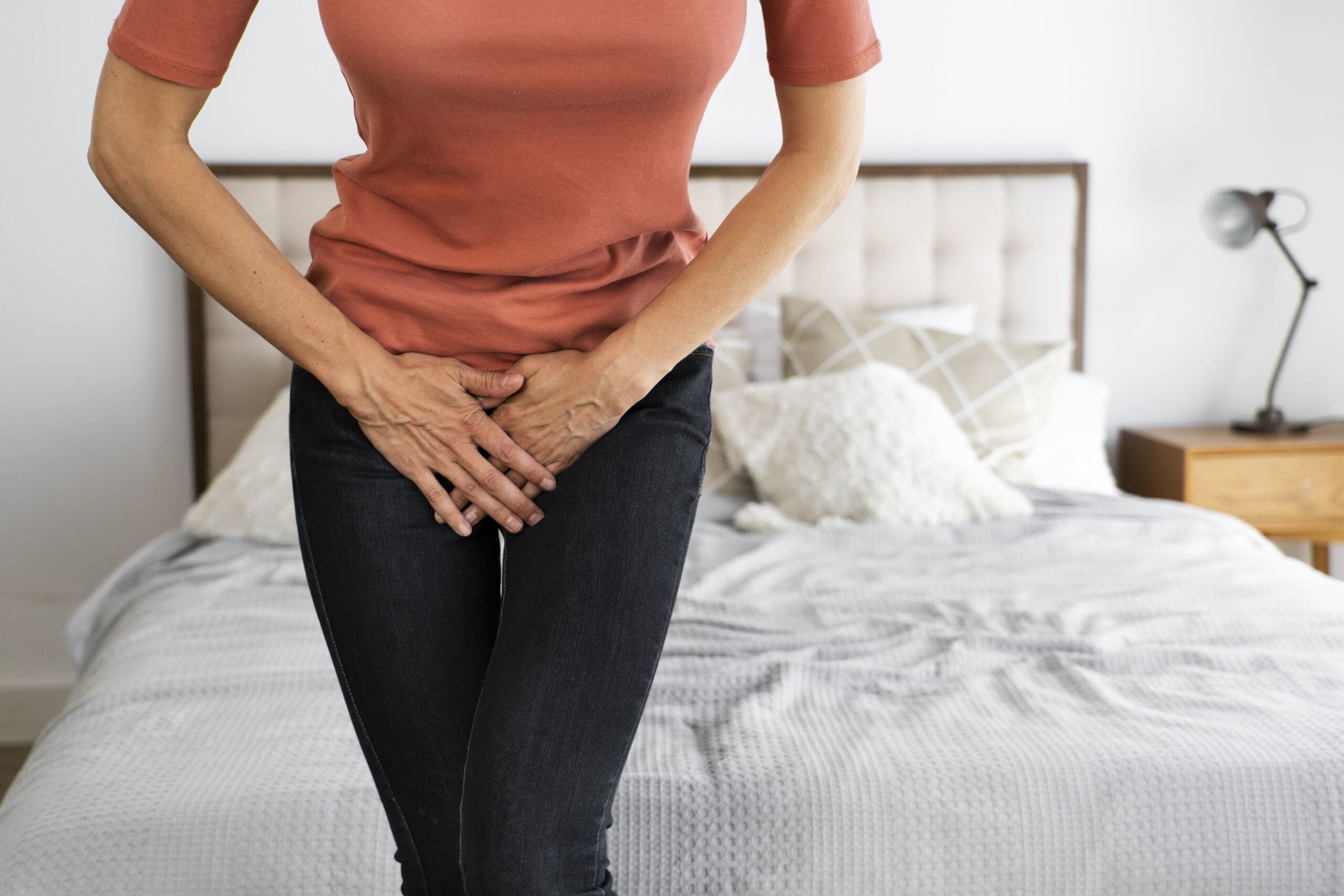 Woman crossing her legs and holding her bladder to show symptoms of urinary incontinence before Emsella treatment.