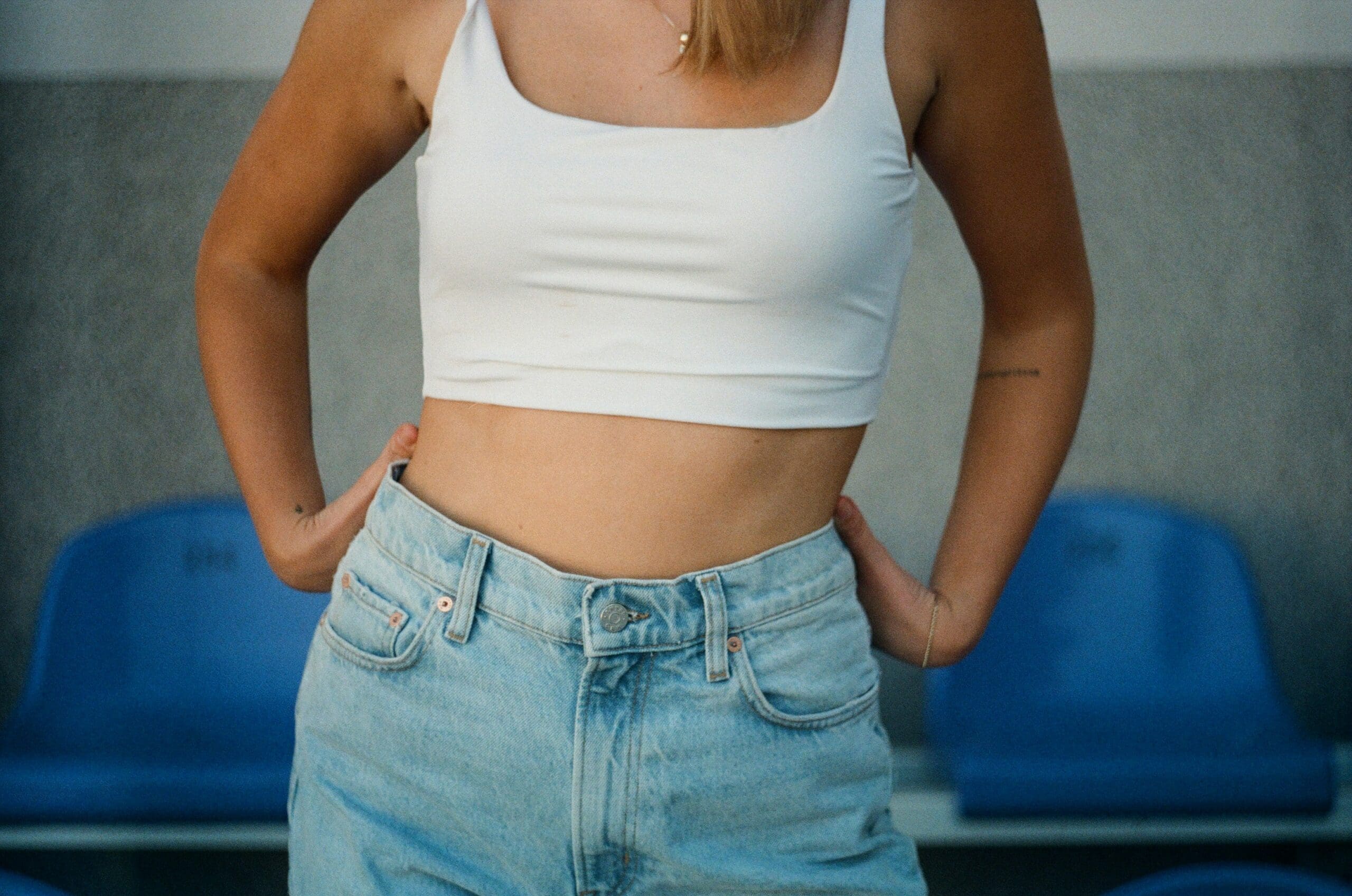 Woman in white crop top and jeans showing toned torso, representing weight loss for women over 40