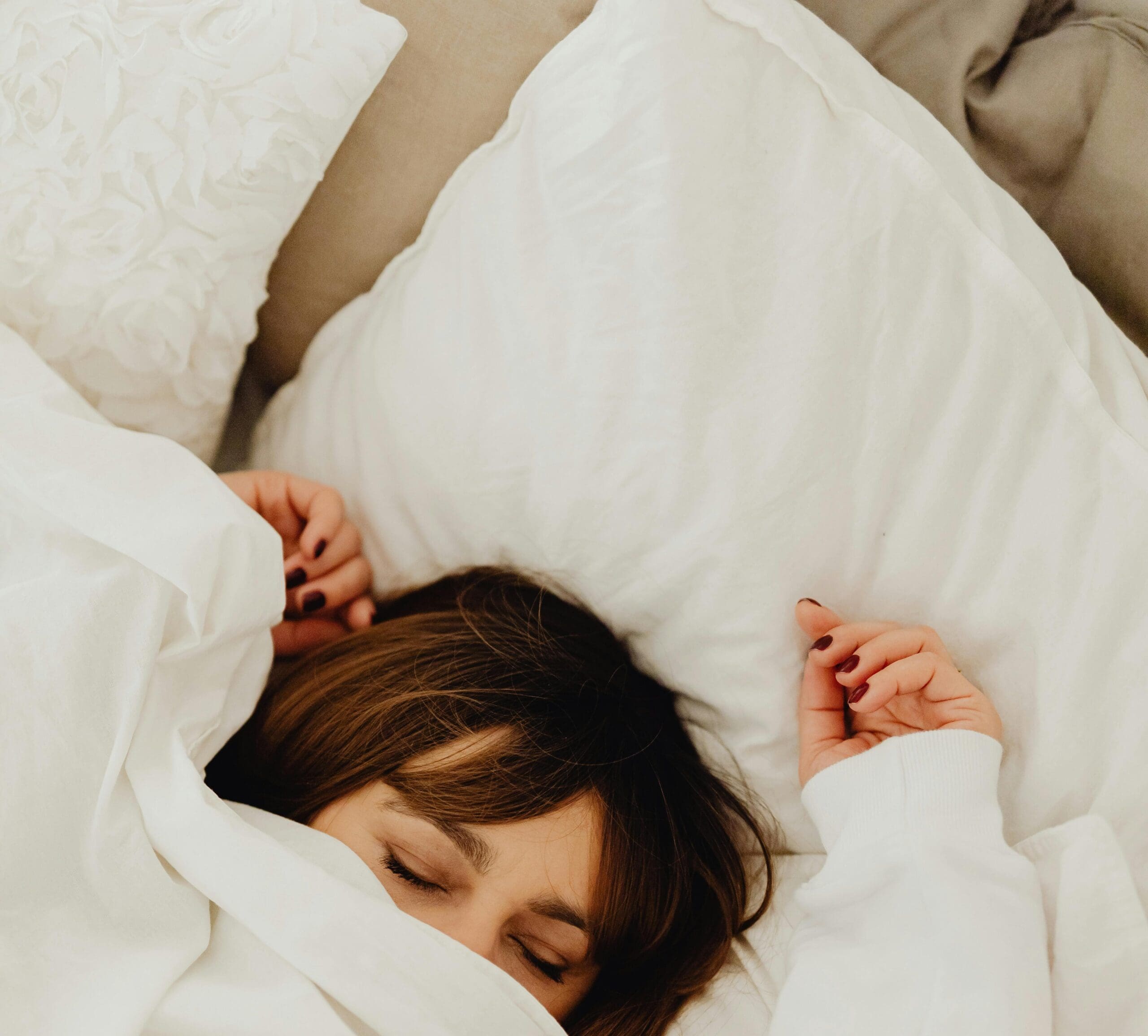 Woman lying in bed feeling exhausted, representing fatigue caused by hormone imbalance in women