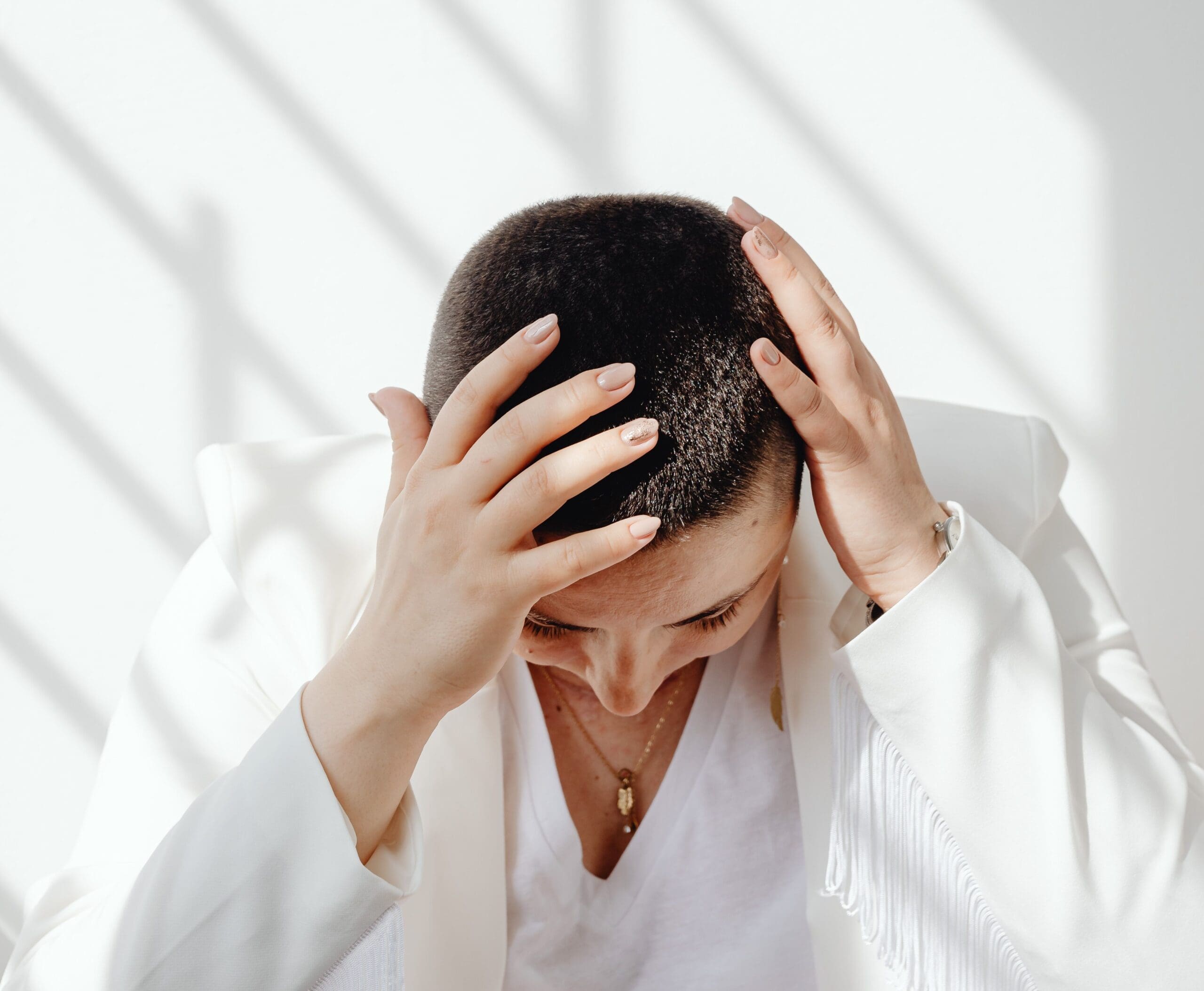 Woman holding her head in frustration, representing brain fog, memory concerns, and hormone imbalance. Wellness and Hormone Health in Centennial, CO helps women identify hormonal and thyroid-related causes of cognitive symptoms.